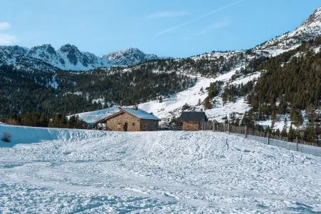 Snow-covered mountain landscape with traditional stone cabins in Andorra, a peaceful winter setting for a family travel escape in the Pyrenees