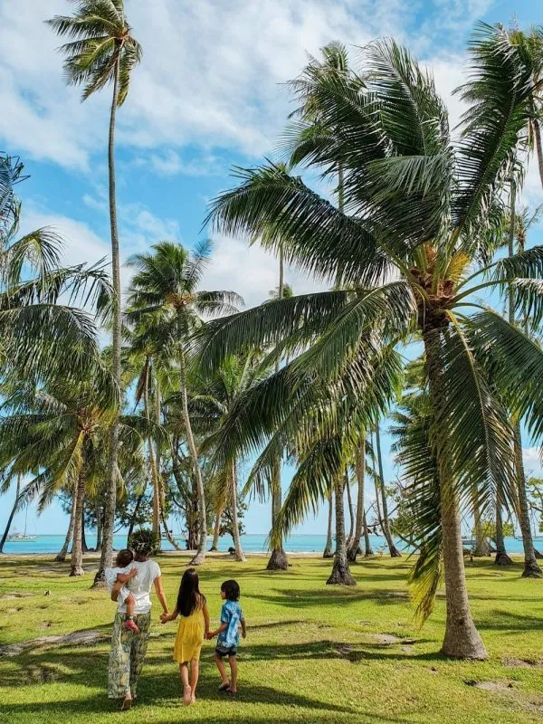 Family walking among palm trees in Moorea, Tahiti, French Polynesia during a travel with kids adventure.