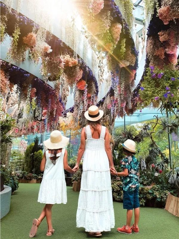 Mother and children admiring a colorful hanging floral installation at Gardens by the Bay in Singapore during an inspiring family travel experience