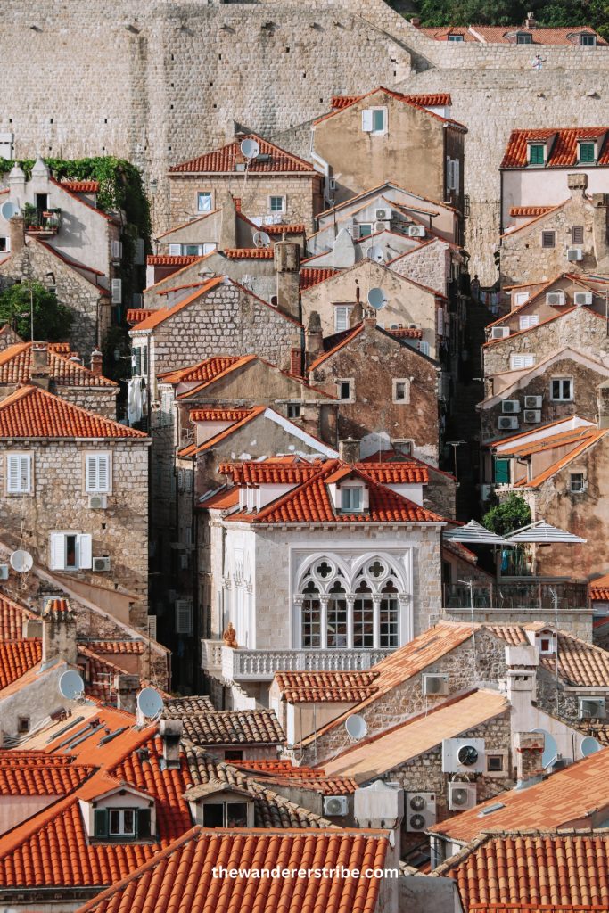 Close-up view of red-tiled rooftops and stone houses packed tightly together in Dubrovnik’s Old Town, highlighting the medieval architecture. Road trip in Croatia