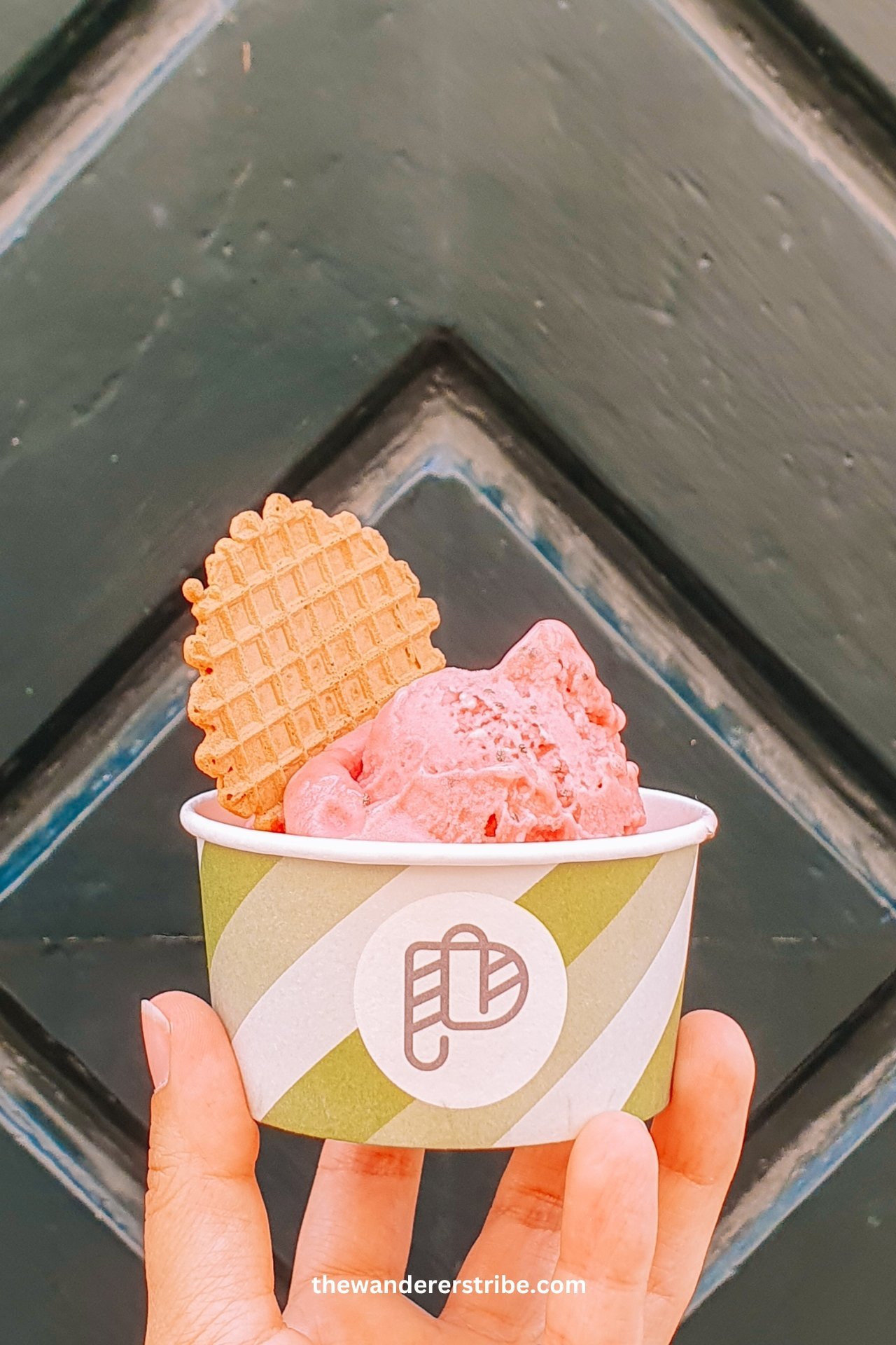 Close-up of raspberry gelato in a green-striped cup with a wafer biscuit in Dubrovnik, Croatia.