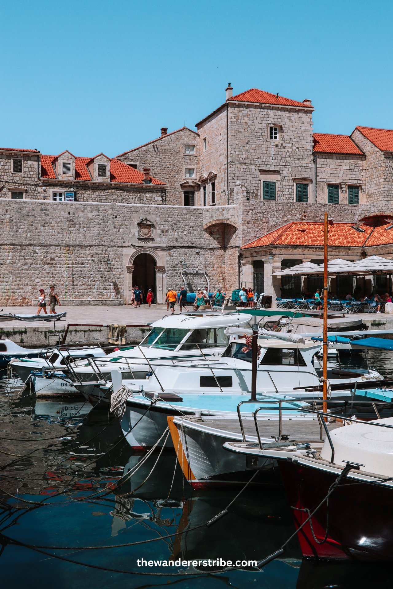 Small boats moored at Dubrovnik’s Old Town harbour near the stone city walls.