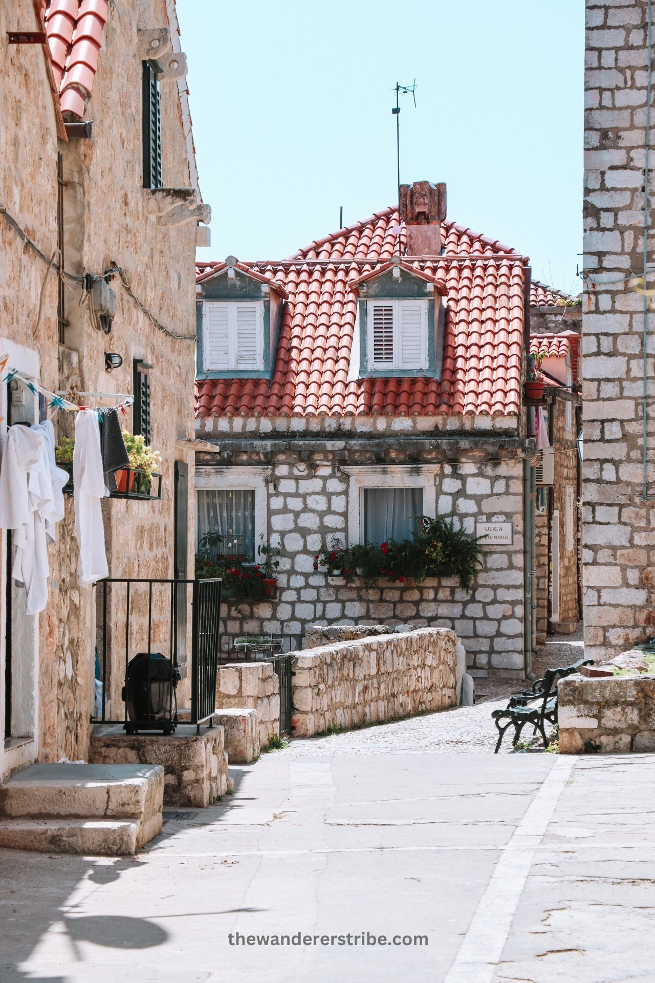 Stone houses with red-tiled roofs and flower boxes in a quiet neighbourhood of Dubrovnik Old Town.