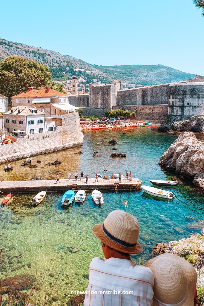 kids watching down Dubrovnik's West Harbour with boats, kayaks, and medieval walls on a sunny day