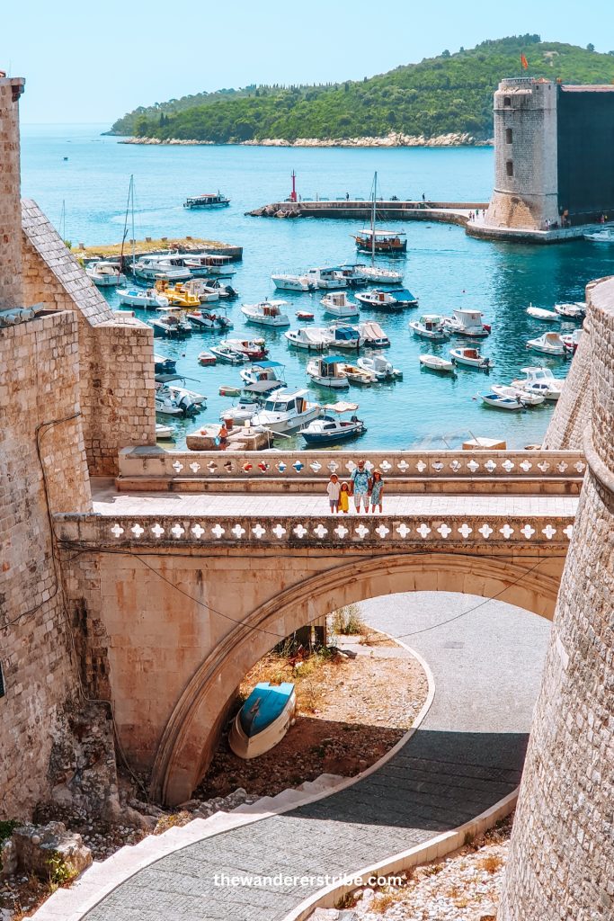 Family standing on the bridge at Ploče Gate, looking at Dubrovnik’s old port filled with boats during a kids-friendly city visit