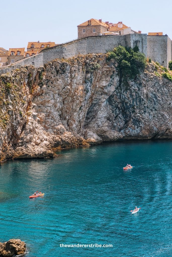 Kayaks paddling near the rocky coastline below Dubrovnik’s city walls, a fun activity for families and children
